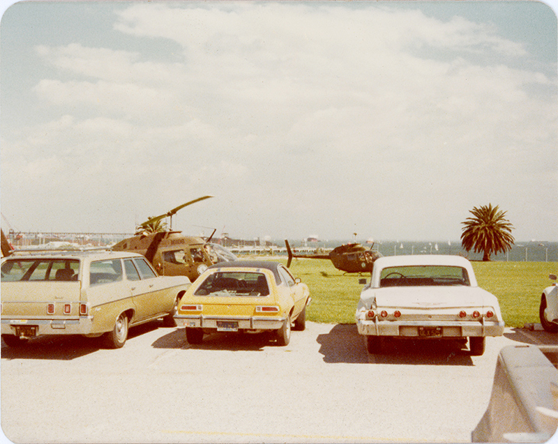 Vintage photograph of cars parked in front of an airfield